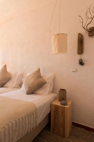 a bedroom with a bed with white sheets and a table at Utopia in Aljezur