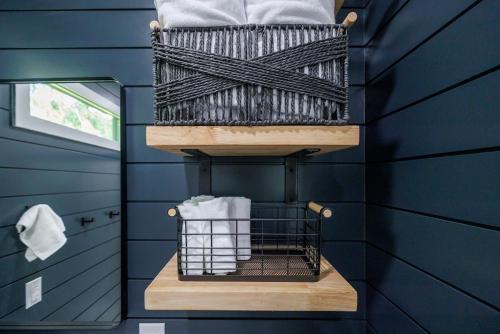 a blue bathroom with a basket of towels on a shelf at Whispering Firefly Escape MicroCabin in Broken Bow