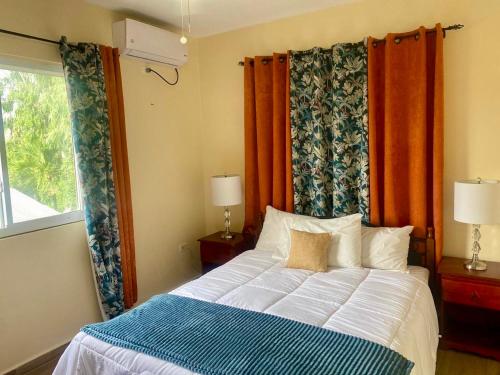 a bedroom with a bed with orange curtains and a window at Villa Conochi in Philipsburg