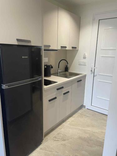 a kitchen with a black refrigerator and a sink at Kostas Studios in Faliraki