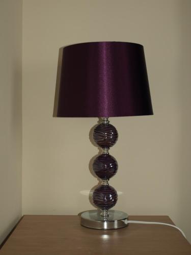 a lamp sitting on a table with a purple lamp shade at Argyle Lodge in Rush