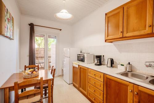 a kitchen with wooden cabinets and a table and a sink at Alexandros House in Agios Gordios Beach on Corfu in Agios Gordios