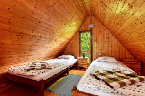 two beds in a log cabin with a window at Erdei Kabin Nagymaros in Nagymaros