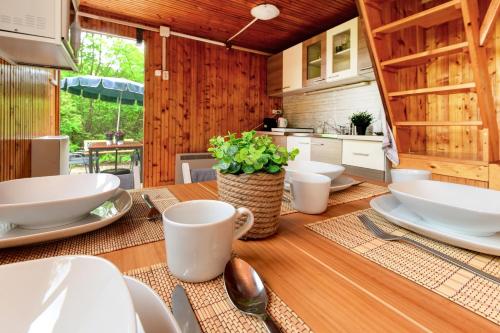 a kitchen with a wooden table with white dishes on it at Erdei Kabin Nagymaros in Nagymaros