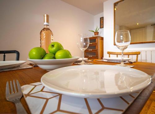 a table with a bowl of apples and wine glasses at Margate Old Town & Beach, Stylish 3 bed House with Garden in Margate