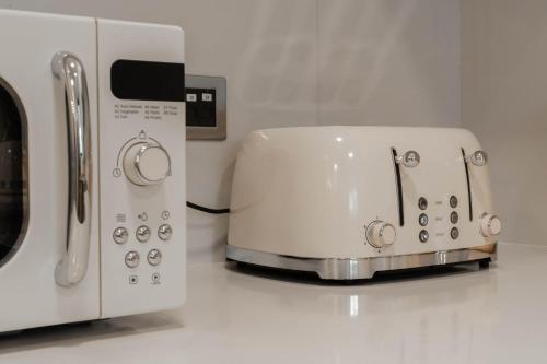 a white toaster sitting next to a microwave on a counter at Abu Dhabi 4BR Villa - Victorian-Inspired Stay in Abu Dhabi