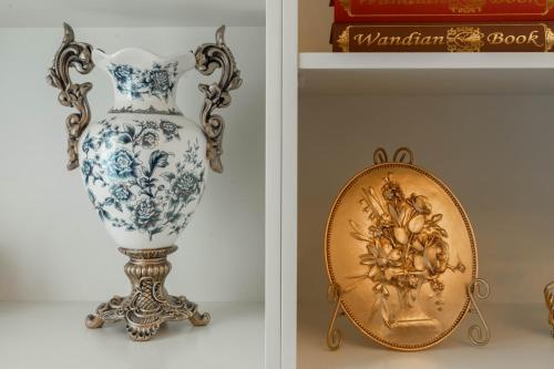 a blue and white vase on a stand next to a gold mirror at Abu Dhabi 4BR Villa - Victorian-Inspired Stay in Abu Dhabi