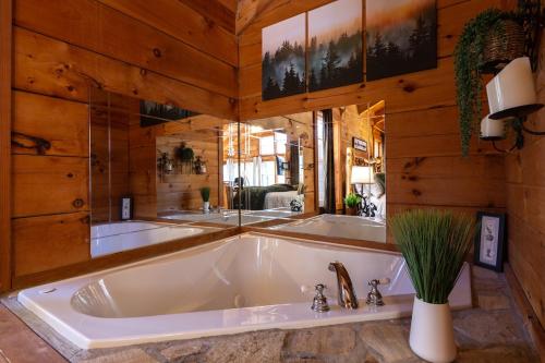 eine große weiße Badewanne in einem Zimmer mit Holzwänden in der Unterkunft Bear's Den Couples Cabin Hot Tub Pets in Sautee Nacoochee
