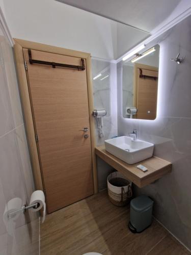a bathroom with a sink and a door with a mirror at Pnoe Studios in Nea Moudania