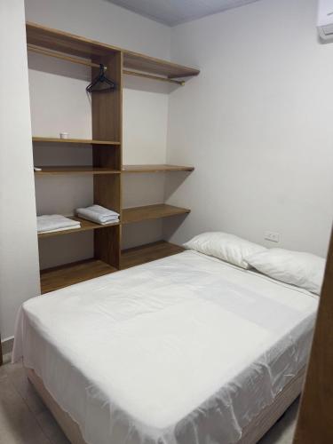 a bedroom with a white bed and shelves at Apartamento Loma Verde in Necoclí