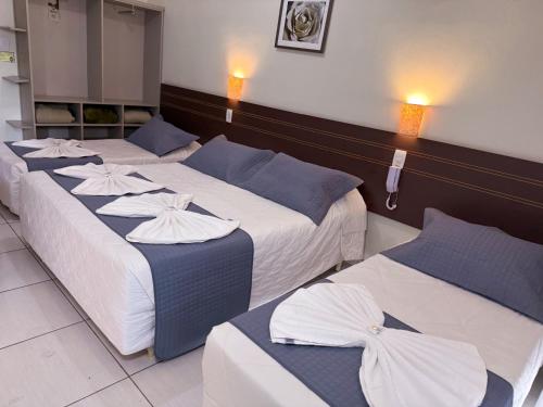 three beds in a hotel room with white and blue at Hotel do Reinildo I in Cachoeira Paulista