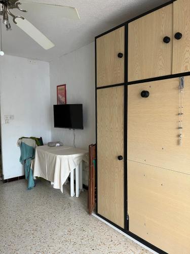 une pièce avec une table, une télévision et un placard dans l'établissement Joana's House, à La Grande Motte