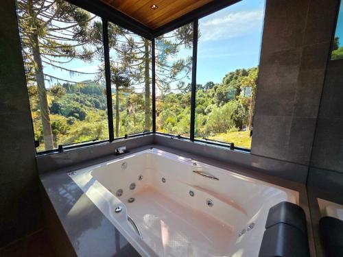 a large white tub in a room with windows at Cabanas Alto Padrão com Jacuzzi, Lareira e cachoeira exclusiva in Urupema