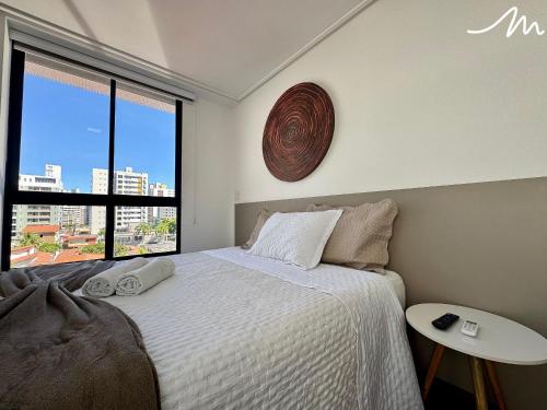 a bedroom with a bed and a large window at Move - Tambaú in Tambaú