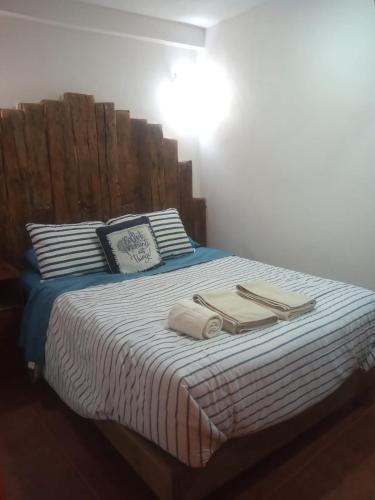 萨卡特兰Posada Las vigas的一张带木制床头板和毛巾的床