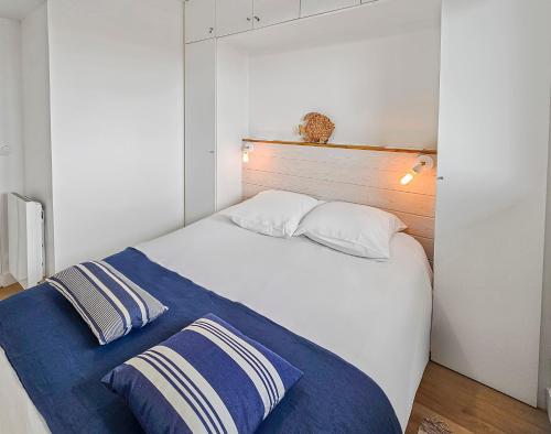 - une chambre avec un lit blanc et une couverture bleue dans l'établissement South-facing terrace, direct beach access, à Cabourg
