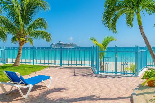 a blue chair and palm trees and a cruise ship at Villas on Great Bay VILLA FOXIE in Philipsburg