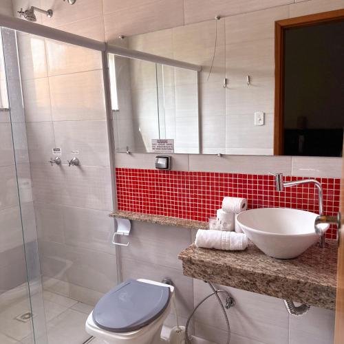 a bathroom with a sink and a toilet and a mirror at Hotel do Reinildo I in Cachoeira Paulista