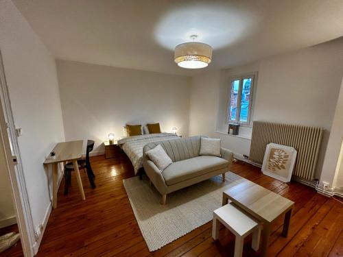un salon avec un lit, un canapé et une table dans l'établissement Appartements Plantagenet - Le 27, au Mans