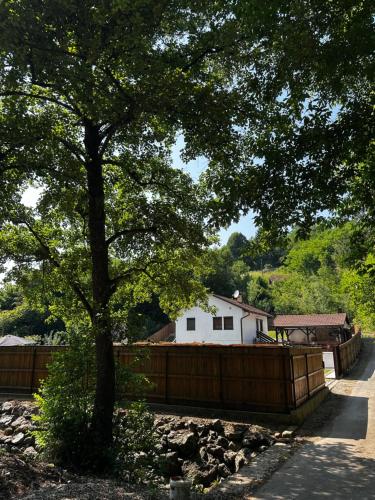 a fence with a tree in front of a house at Holiday home with private pool ''Lux Banja Luka'' in Banja Luka