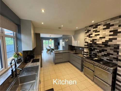 a large kitchen with a sink and a stove at The Plum Tree - 5 luxury modern bedrooms in Melton Mowbray