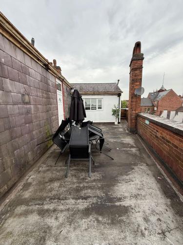 two chairs and an umbrella sitting on the side of a building at Charming Wolverhampton Apartment with Private Entrance in Wolverhampton