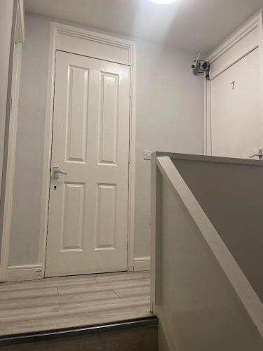 an empty room with a white door and a staircase at Nightingale Ensuite Budget Rooms in Woolwich
