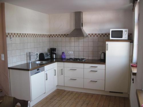 eine kleine Küche mit weißen Schränken und einer Mikrowelle in der Unterkunft Ferienhaus Zum Landsknecht in Lissendorf
