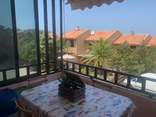 a table on a balcony with a view of a house at CASA STINTINO tra Ginepri e Mare in Stintino