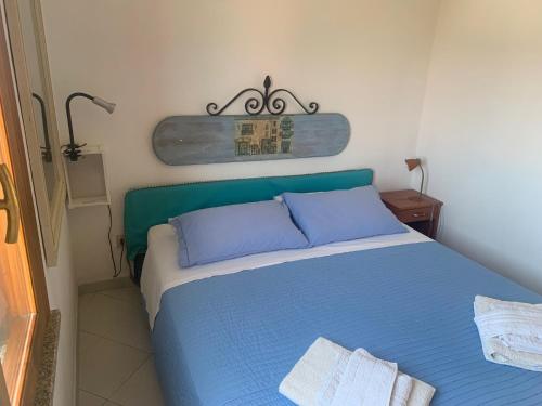 a bedroom with a blue bed with a green headboard at CASA STINTINO tra Ginepri e Mare in Stintino