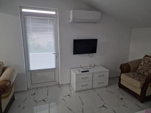 sala de estar blanca con TV y silla en Celas Home, en Pogradec