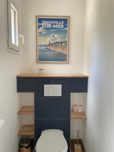 a bathroom with a toilet and a poster on the wall at Le Bras d 'Or in Pont-lʼÉvêque