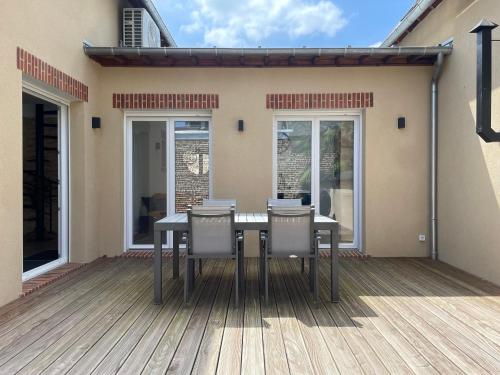 a table and chairs on a deck in front of a house at Le Bras d 'Or in Pont-lʼÉvêque