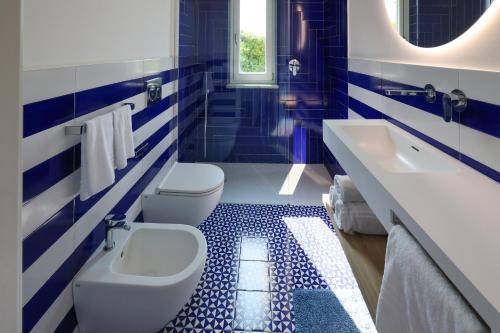 a blue and white bathroom with two toilets and a sink at Hotel Boutique Ideal in Ischia