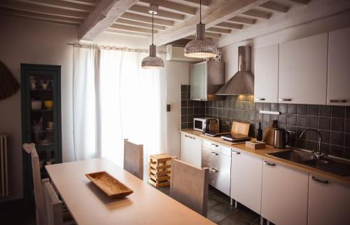 a kitchen with white cabinets and a table and a window at Mecana Home - 20 minuti dalle terme di Saturnia in Manciano