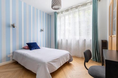 a bedroom with a bed and a window and a chair at 4-room apartment Place de la Mairie - City Center in Bois-Colombes