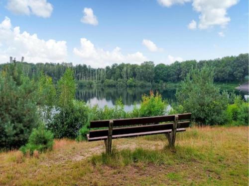a park bench sitting in the grass near a lake at Chalet with covered terrace in the Leukermeer in Well