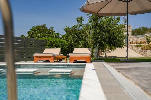 two chairs and an umbrella next to a swimming pool at Olive Scent in Gouves