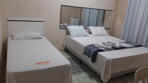 2 Betten in einem kleinen Zimmer mit Spiegel in der Unterkunft O melhor custo benefício da cidade - Hotel Ceará in Pinheiro