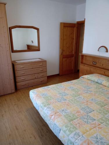 a bedroom with a bed and a dresser and a mirror at Appartamenti Piller Roner Roberto in Sappada