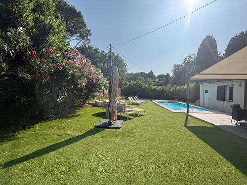 une cour arrière avec une piscine, un parasol et une pelouse dans l'établissement Villa St Joseph, à Saint-Tropez