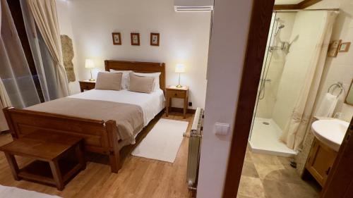 a bedroom with a bed and a bathroom with a shower at Quinta de CasalMato in Resende