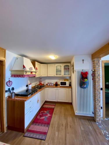 a kitchen with white cabinets and a red rug at La casa di Rosy in Enego