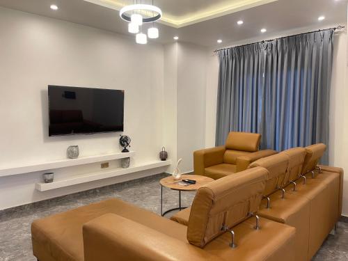 a living room with a couch and chairs and a tv at Kassardjian Apartments in Accra