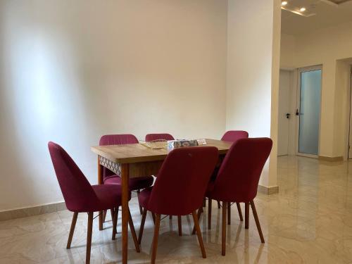 a wooden table with red chairs in a room at Kassardjian Apartments in Accra