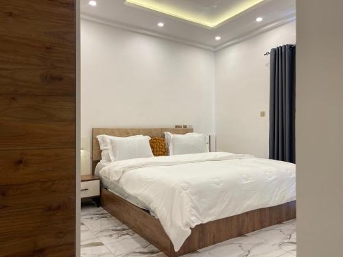 a bedroom with a large bed with white sheets and pillows at Kassardjian Apartments in Accra