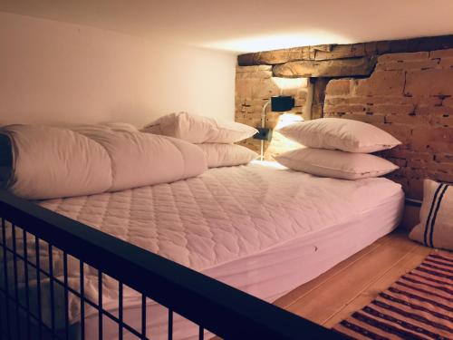 Bett mit weißen Kissen und Ziegelwand in der Unterkunft El antiguo taller de Guantes in Madrid