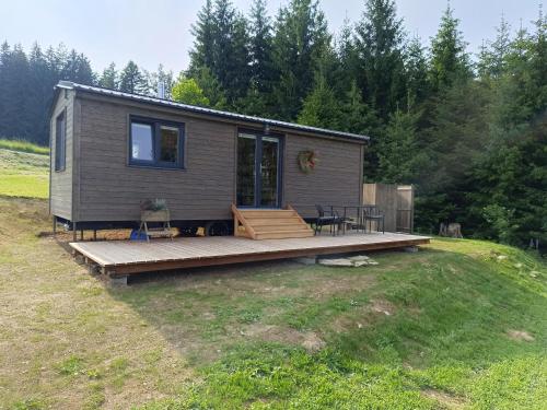 a tiny house with a deck in a field at Maringotka U Skalek in Hlavňovice