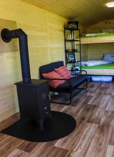 a room with a stove and a chair and a bed at Maringotka U Skalek in Hlavňovice