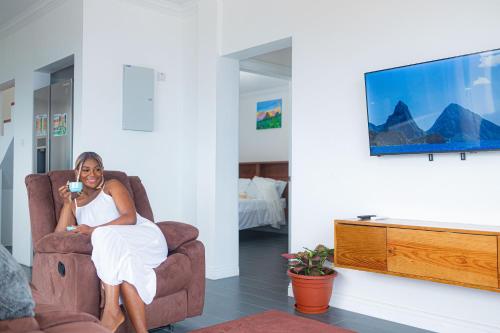 a woman sitting in a chair holding a drink at Majestic Dream Villas in Choiseul